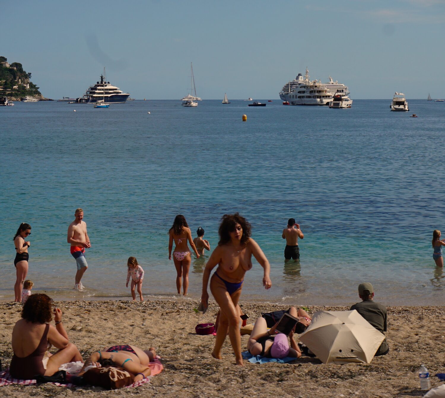 Swimmers in turquoise Mediterranean water below the coast road