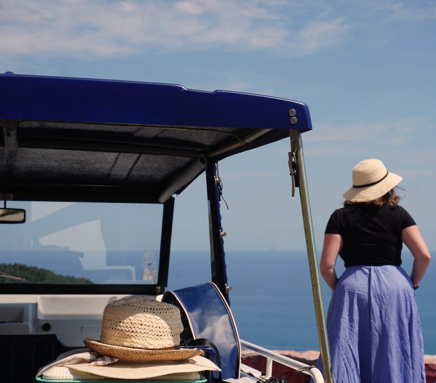 Sun hats on the seat of a classic car with a sea view